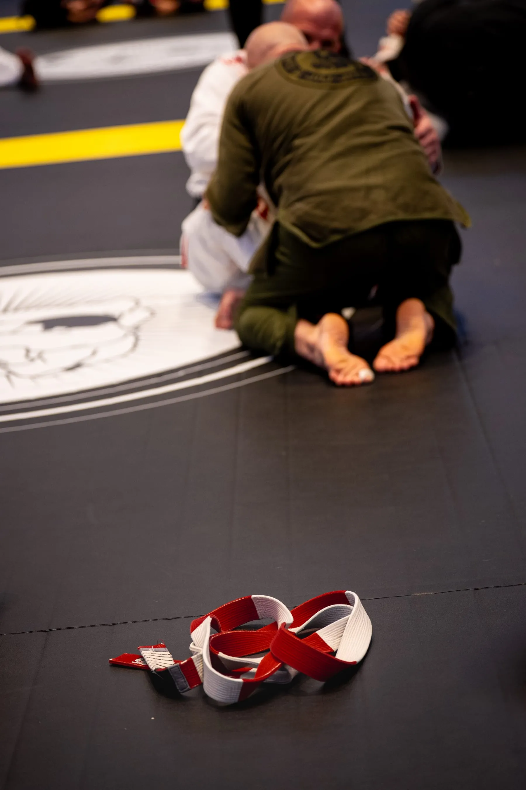 A red-and-white coral belt laid out alone on the mat