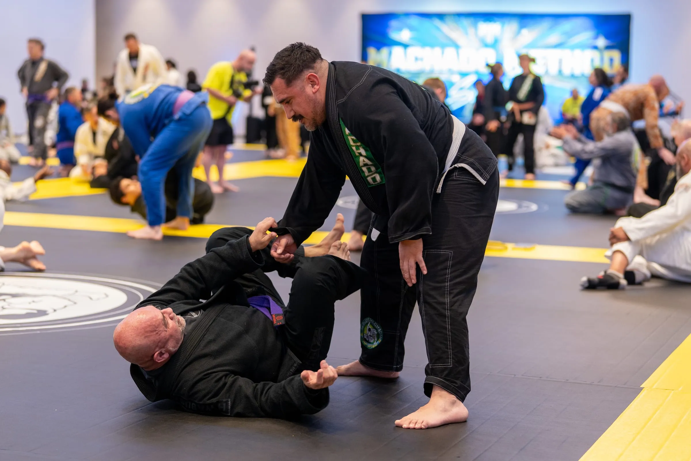A black belt working from standing over a partner during live rolling